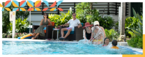 senior couple sitting poolside with legs in the water splashing each other