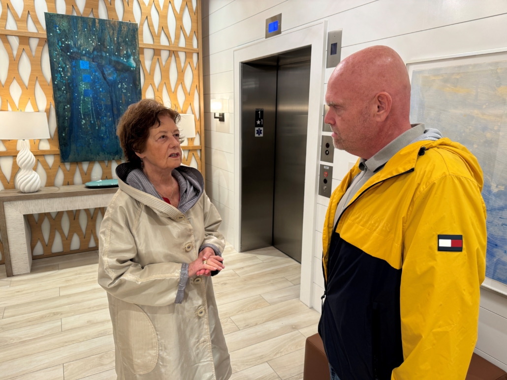 concerned senior woman wearing trench coat talking to leader wearing raincoat