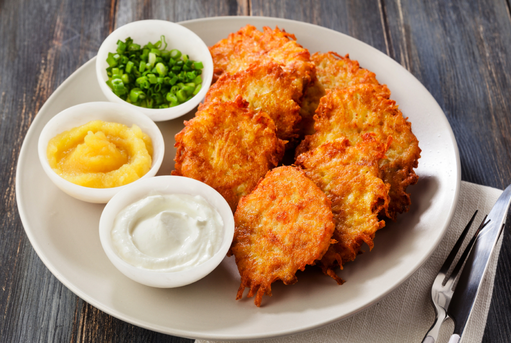 Potato pancakes on a plate with sour cream, applesauce and chives