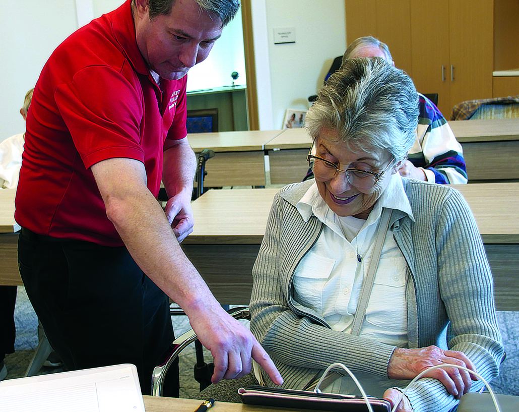 technology teacher helping a senior with her tablet