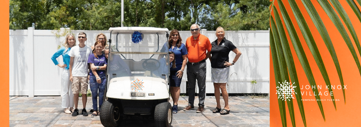 John Knox Village leadership with members of ScentsAbility posing with a golf cart JKV donated
