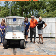 John Knox Village leadership with members of ScentsAbility posing with a golf cart JKV donated