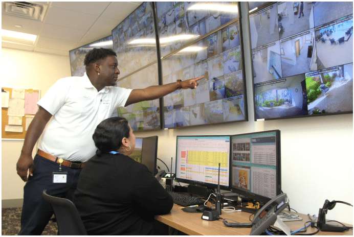 Security trainee sitting with JKV Security Manager pointing to a monitor 