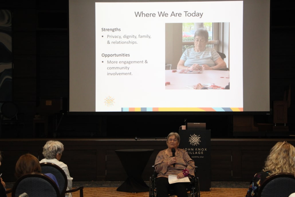 Resident Marilyn Blessing speaks to crowd in auditorium
